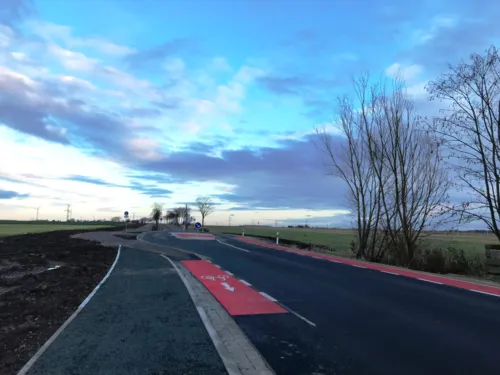 Eine Stra&szlig;e mit Querungshilfe und Schutzstreifen f&uuml;r Radfahrende